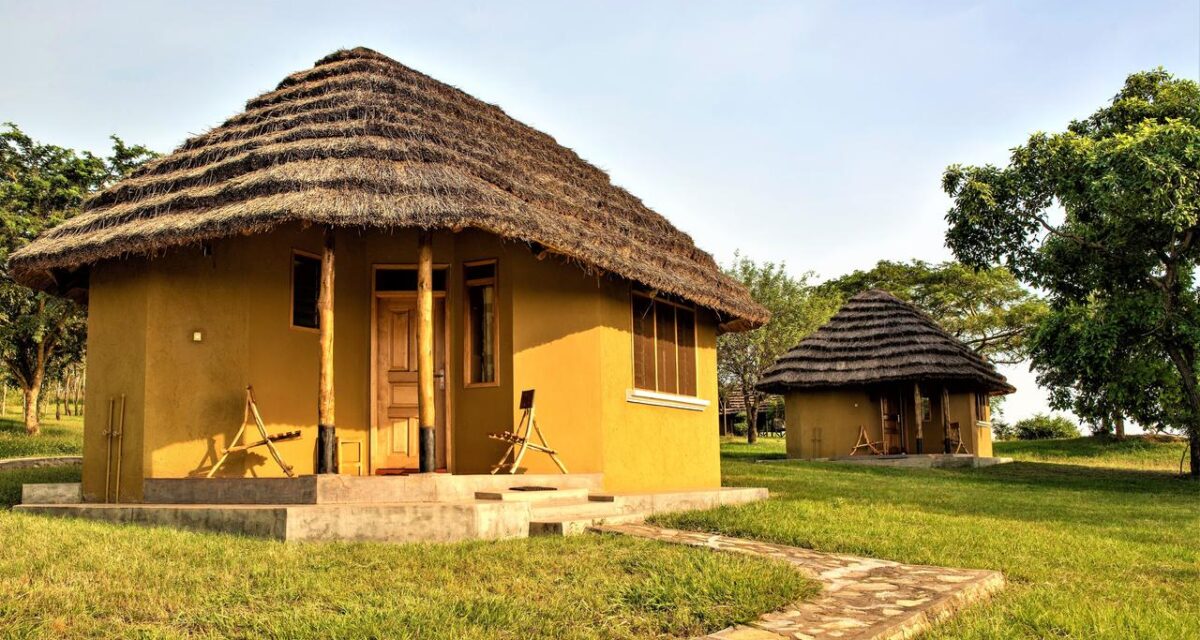 Thatched-roof cottages set in green lawns at Bwana Tembo Camp near Murchison Falls